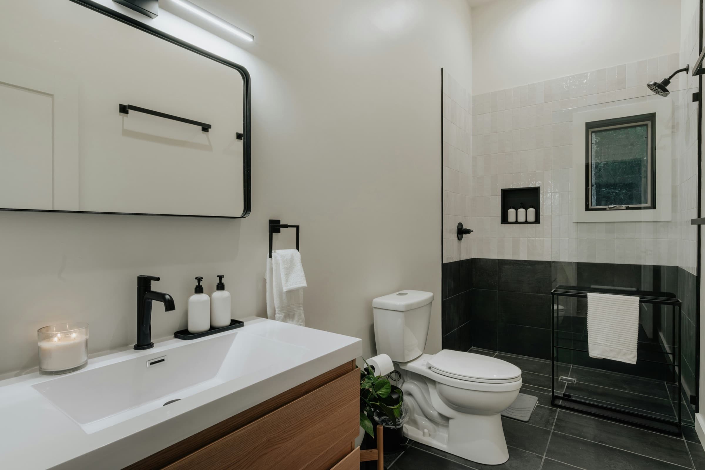Modern bathroom with a black faucet, white sink, toilet, and shower fixtures