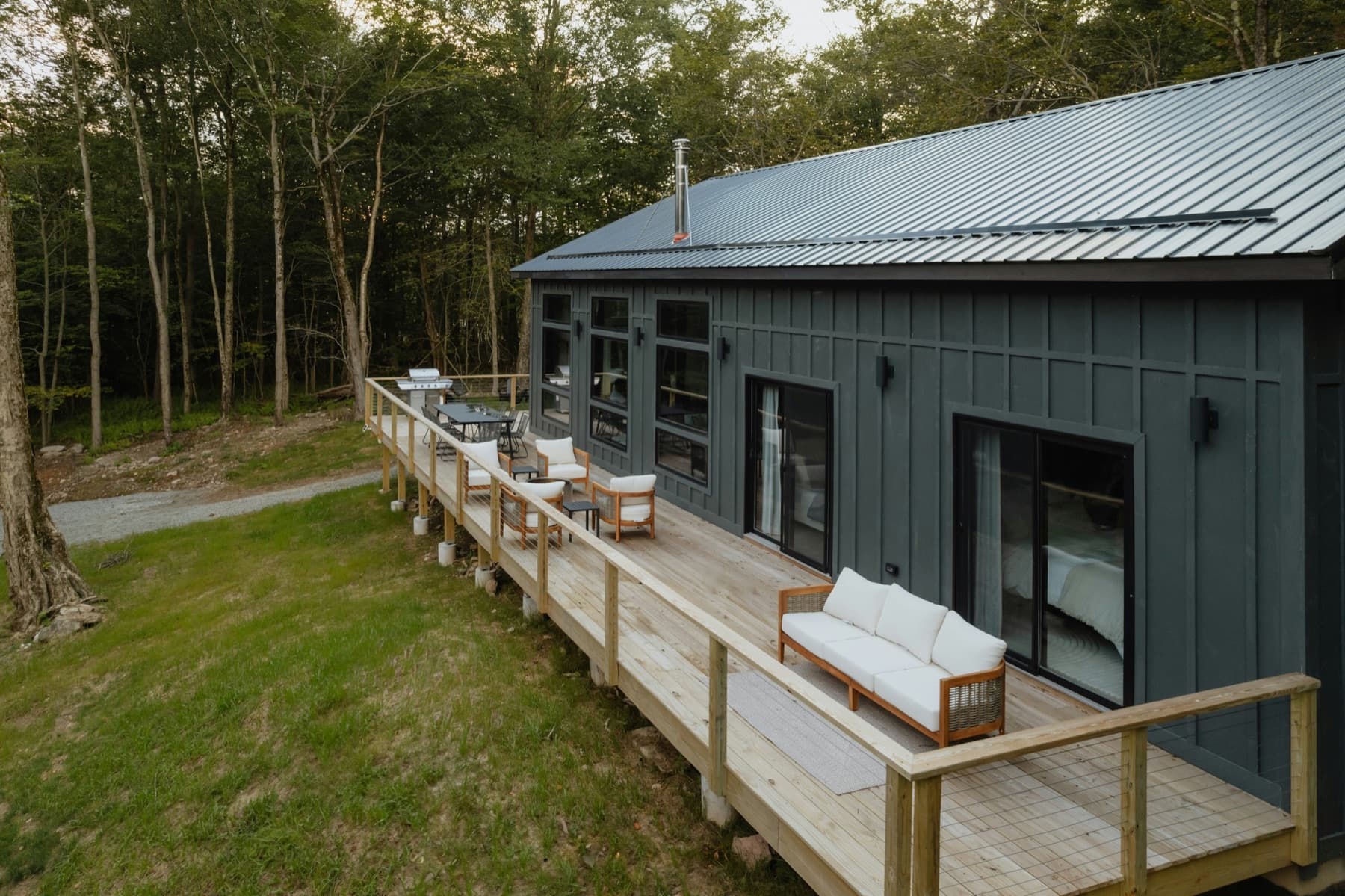 Wood deck with cable railing beside a dark modern home