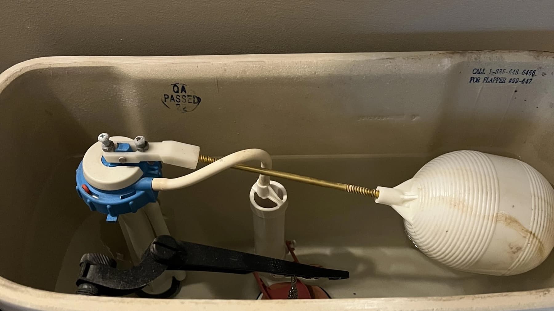 Open toilet tank showing the fill valve, float, and flapper