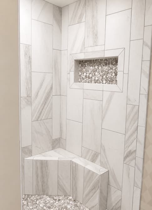 White and gray shower tile with a mosaic niche and corner bench
