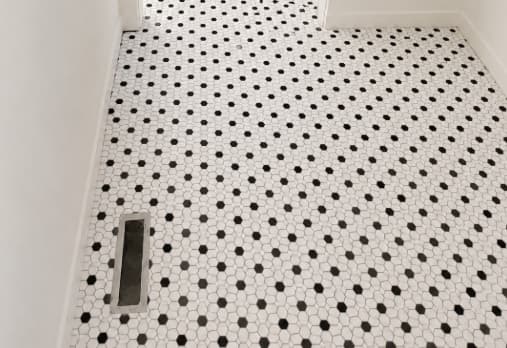 Black and white mosaic tile floor with flush register