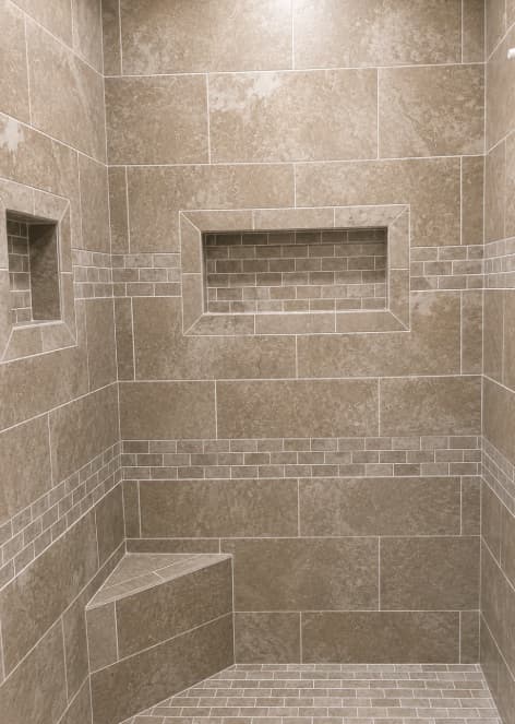 Tan tile shower with two recessed niches and a corner seat