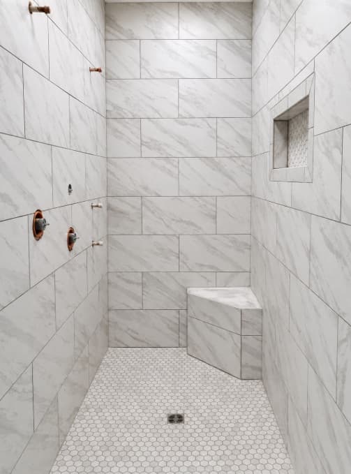 White marble-look shower with built-in corner bench